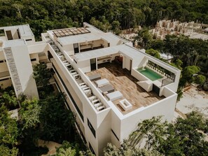 A modern building with multiple levels, a rooftop deck with outdoor seating, and a swimming pool. - Casa Coba Plunge Pool Beach Club Aldea Zama (Tulum)