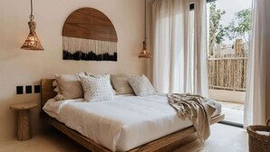 A bedroom with a wooden bed, a round wall decoration, and two hanging light fixtures. - Casa Coba Plunge Pool Beach Club Aldea Zama (Tulum)
