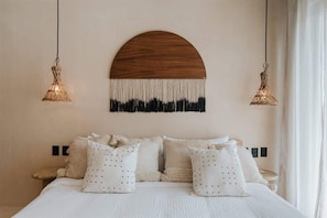 A bedroom with a bed, pillows, a wall-mounted wooden piece, and two hanging light fixtures. - Casa Coba Plunge Pool Beach Club Aldea Zama (Tulum)