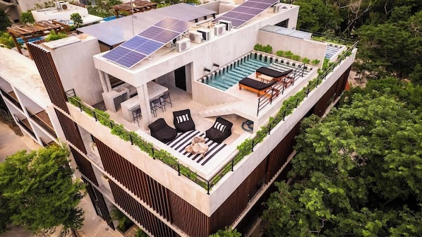 A rooftop pool with lounge chairs, a small bar area, and solar panels. - Jungle Modern Loft 101 Aldea Zama Walk Everywhere (Tulum)