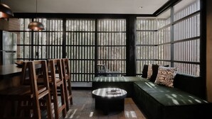 A modern interior with a dining area, a sofa, and large windows. - Jungle Modern Loft 101 Aldea Zama Walk Everywhere (Tulum)