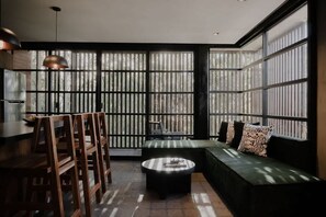 A modern interior with a dining area, a sofa, and large windows.
