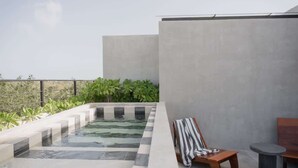 A rooftop pool area with a lounge chair and a small table, surrounded by greenery and a concrete wall. - Jungle Loft 203 Penthouse Aldea Zama Private Pool (Tulum)