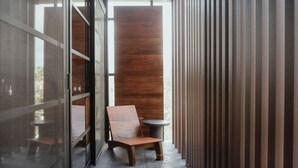 A narrow corridor with a wooden bench and a small round table, leading to a room with a large wooden panel wall. - Jungle Loft 203 Penthouse Aldea Zama Private Pool (Tulum)