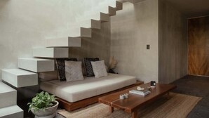 A modern living room with a sofa, coffee table, and a unique staircase design. - Jungle Loft 203 Penthouse Aldea Zama Private Pool (Tulum)