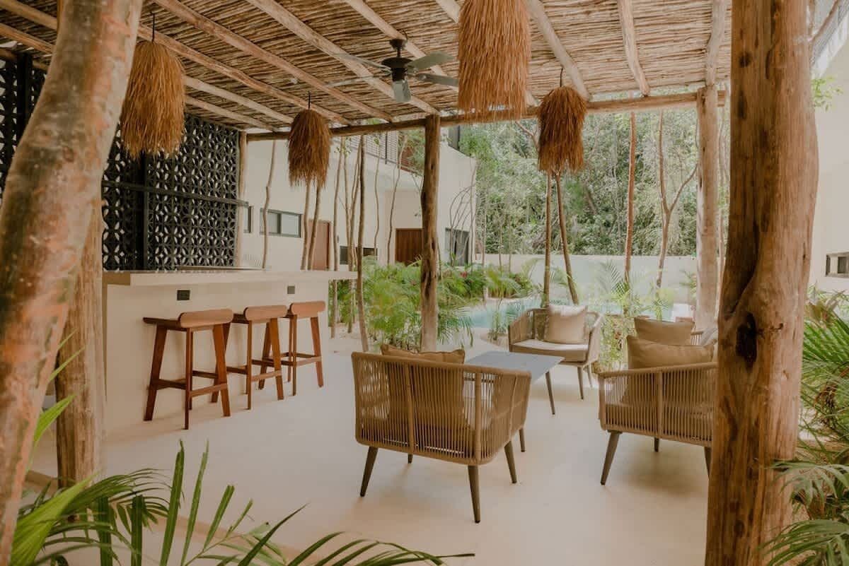 Un espace extérieur aménagé avec des meubles en osier, une piscine et une structure dotée d’un toit de chaume.
