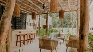 An outdoor seating area with wicker furniture, a pool, and a thatched roof structure. - Casa Coba Boho Private Pool Beach Club Access (Tulum)
