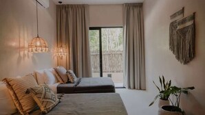 A bedroom with a bed, two bedside tables, a potted plant, and a view of the outdoors. - Casa Coba Boho Private Pool Beach Club Access (Tulum)
