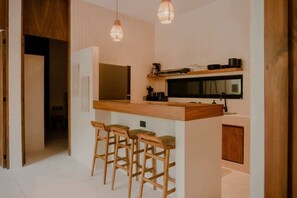 Una cucina moderna con un piano di lavoro in legno, sgabelli da bar, luci a sospensione e forno integrato.