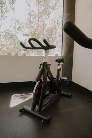 Ein Indoor-Trainingsrad in einem Raum mit großem Fenster, dunklem Boden und weißer Wand.