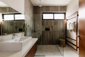 Un baño moderno con un lavamanos grande, una zona de ducha y un espejo.