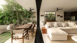 A modern living space with a dining area, a sofa, and a kitchen. - Casa Iguana Private Villa Large Pool Beach Club (Tulum)