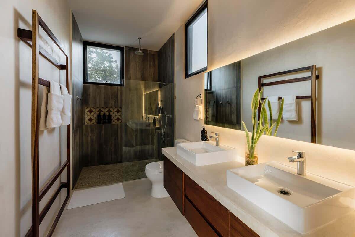 A modern bathroom with a shower, two sinks, and a large mirror.