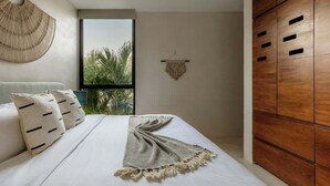 A modern bedroom with a large bed, a wooden wardrobe, and a view of palm trees through a window. - Casa Iguana Private Villa Large Pool Beach Club (Tulum)