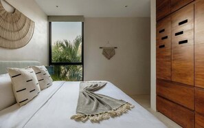 Une chambre à coucher moderne avec un grand lit, une armoire en bois et une vue sur les palmiers par la fenêtre.
