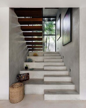 Un escalier avec une finition en béton, des marches en bois et un panier tressé à sa base.