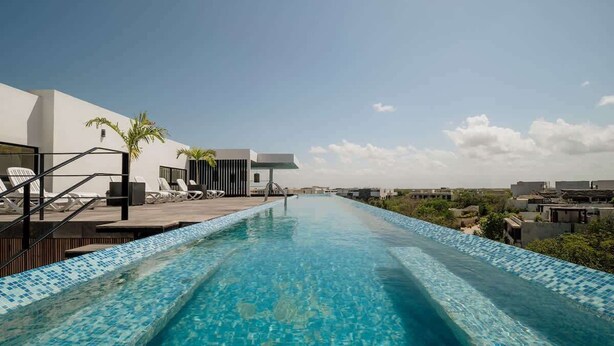 Ein Dachpool mit Infinity-Kante und freiem Blick auf die Stadtlandschaft, umgeben von moderner Architektur und Palmen.