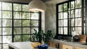 Une cuisine moderne avec un grand îlot central, des tabourets en bois et un luminaire suspendu.