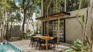 Un espace de restauration extérieur moderne, doté d’une piscine et entouré d’arbres et de plantes.