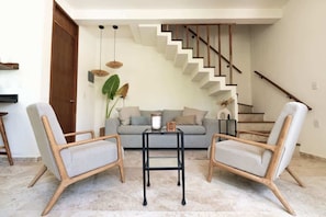A living room with two armchairs, a sofa, a coffee table, and a staircase. - Casa Kaatal Sunny Penthouse Pool Beach Club Access (Tulum)