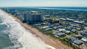 An aerial view of a coastal residential area with beachfront properties, a large hotel complex, and a marina.