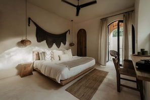 A bedroom with a bed, a ceiling fan, a woven light fixture, a wooden headboard, and a view through a door. - Tulipan Bohemian Villa Beach Club Access Gated (Tulum)
