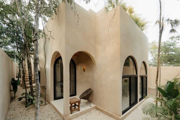 A building with arched windows and a small seating area with a chair and table.
