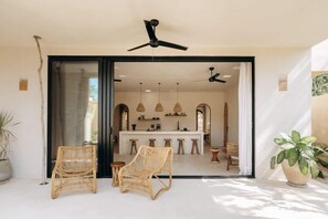 A modern kitchen with a central island, two wicker chairs, and a ceiling fan.