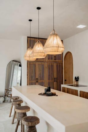 A modern kitchen with a central island, wooden stools, and pendant lighting. - Tulipan Bohemian Villa Beach Club Access Gated (Tulum)