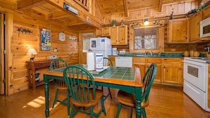 A wooden cabin interior with a dining table, chairs, a refrigerator, and a microwave. - A Bear's View-Gatlinburg, Resort Setting, Sleeps 6 (GATLINBURG)