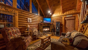 A log cabin interior with a fireplace, wooden furniture, and a television. - A Bear's View-Gatlinburg, Resort Setting, Sleeps 6 (GATLINBURG)