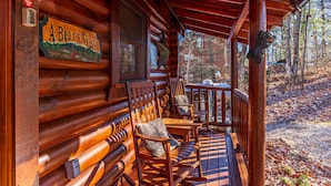 A wooden cabin with a porch, a sign reading "A Bear's View," and a bear sculpture. - A Bear's View-Gatlinburg, Resort Setting, Sleeps 6 (GATLINBURG)