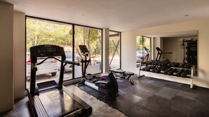 A home gym with exercise equipment, large windows, and a view of the outdoors.