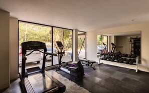 A home gym with exercise equipment, large windows, and a view of the outdoors.