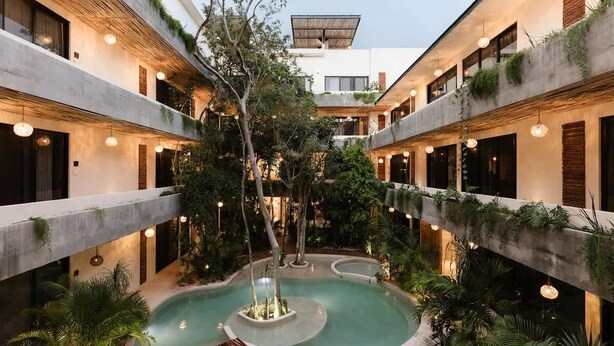 A multi-level building with a central pool, surrounded by greenery and multiple balconies.