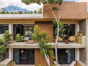 A modern multi-story building with balconies, outdoor seating, and greenery.