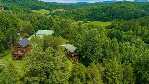 A large wooden cabin with a green roof surrounded by dense forest. - A Getaway With A View-Secluded Near Gatlinburg (SEVIERVILLE)