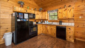 A wooden cabin kitchen with a refrigerator, stove, microwave, and dishwasher. - A Getaway With A View-Secluded Near Gatlinburg (SEVIERVILLE)