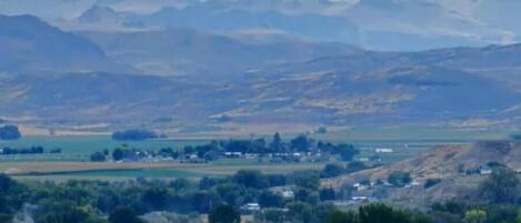 A rural landscape with rolling hills, a small village, and a body of water.