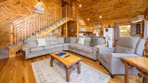 A wooden interior with a staircase, a sectional sofa, a chair, and a coffee table.