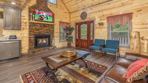 A log cabin interior with a fireplace, seating area, and a television. - Game Loft*Private Pool*1 mile to Pigeon Forge Parkway (PIGEON FORGE)