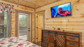 A wooden cabin room with a bed, a TV, and a wooden cabinet. - Game Loft*Private Pool*1 mile to Pigeon Forge Parkway (PIGEON FORGE)
