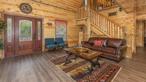 A wooden interior with a staircase, a brown leather sofa, a blue armchair, and a wooden coffee table. - Game Loft*Private Pool*1 mile to Pigeon Forge Parkway (PIGEON FORGE)
