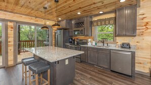 A modern kitchen with wooden ceiling, granite countertops, stainless steel appliances, and a large island with stools. - Game Loft*Private Pool*1 mile to Pigeon Forge Parkway (PIGEON FORGE)