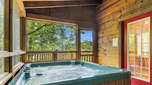 A wooden cabin with a hot tub, large windows, and a red door. - Friends/Couples*Game room w/ poker table*Close to everything (PIGEON FORGE)