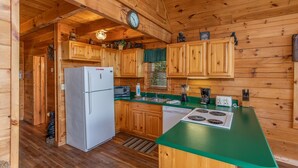 A wooden cabin kitchen with a refrigerator, microwave, sink, and a green countertop. - Angel's Majestic View*Close to Dollywood*Game Room (SEVIERVILLE)