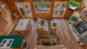 A cozy cabin interior with a dining area, sofa, fireplace, and a TV. - Angel's Majestic View*Close to Dollywood*Game Room (SEVIERVILLE)