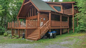 A cabin with a wooden exterior, a balcony, and a staircase leading to the upper level.