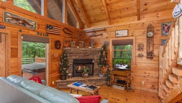 A cozy cabin interior with a stone fireplace, wooden walls, and a leather couch.