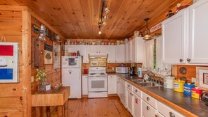 A kitchen with wooden cabinets, a stove, a sink, and various kitchen appliances.